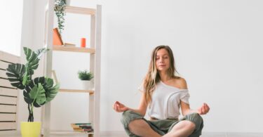 Jovem em posição de lótus enquanto medita. Prática de Mindfulness, Bem-Estar e Autoconhecimento, cuidando da mente e do corpo.