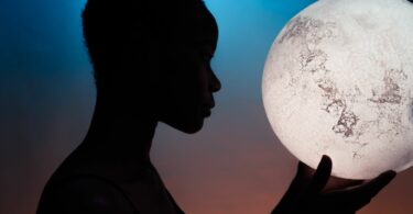 Imagem da silhueta de mulher segurando a Lua, emitindo o conceito de diversidade cósmica.