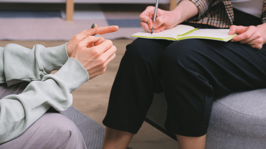 Terapeuta anônima e cliente sentada em poltronas durante sessão no escritório moderno.