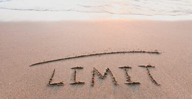 Imagem de uma praia e na areia está escrito a palavra limite em inglês.