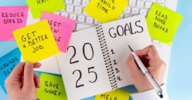 Imagem de um notebook e sobre ela um caderno e vários post-its coloridos com frases e palavras de motivações para o novo ano de 2025.
