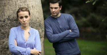 Imagem de um casal encostado em uma árvore. Um do lado do outro, trazendo o conceito de uma reção entre pessoa melancólica e narcisista.