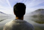 Imagem de um lago e em volta dele, duas montanhas. Em destaque, um homem, olhando para o futuro, trazendo o conceito de valorização da vida.
