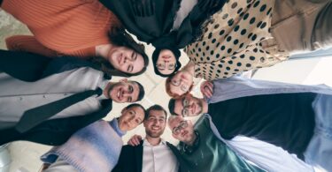 Imagem de um grupo diversificado de profissionais de negócios, abraçados firmemente, simbolizando: unidade, pertencimento, autenticidade e solidariedade.