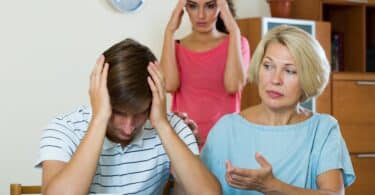Imagem de uma esposa e sua sogra irritadas convernsando com um jovem marido.