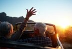 Imagem de um casal 60+ dentro de um carro sem teto, olhando o pôr do sol. Eles estão felizes, vivendo o momento presente.