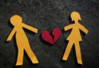 Imagem de um casal desenhando em papel e ao centro a foto de um coração partido, simbolizando o fim do amor.