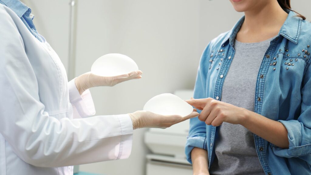 Imagem de um médico mostrando implantes de silicone para aumento de mama para paciente na clínica.

