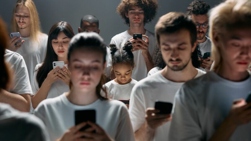 Imagem de várias pessoas engajadas em seus telefones celulares.