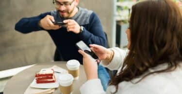 Imagem de dois criadores de conteúdo postando fotos de seu café nas redes sociais.