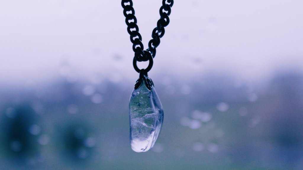 Um cristal está embutido em um colar como um pingente. O colar está suspenso no ar.