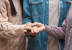 As mãos de duas mulheres e um homem estão no centro da imagem. Eles unem as suas mãos umas com as outras.