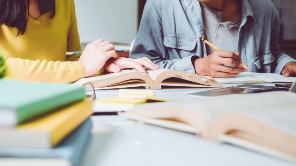 Imagem de uma professora tirando as dúvidas do seu aluno de 12 anos.
