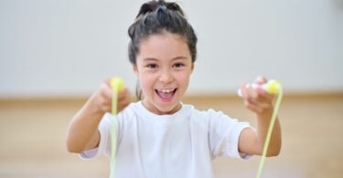 Imagem de uma menina alegre pulando com corda de pular.