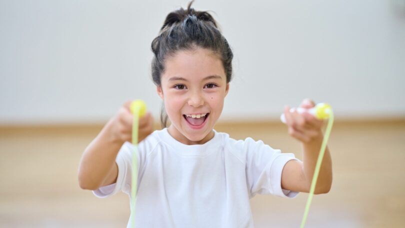 Imagem de uma menina alegre pulando com corda de pular.