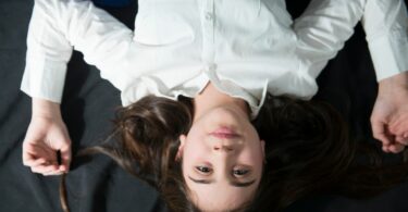 Imagem de uma mulher de camisa branca de cabeça para baixo, trazendo o conceito de impotência.