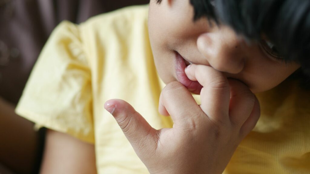 Imagem de uma criança menina roendo as unhas.
