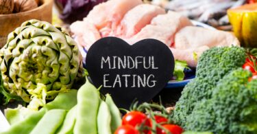 Imagem de vários vegetais, verduras e carne de frango e ao centro uma placa com os dizeres: Mindful Eating.