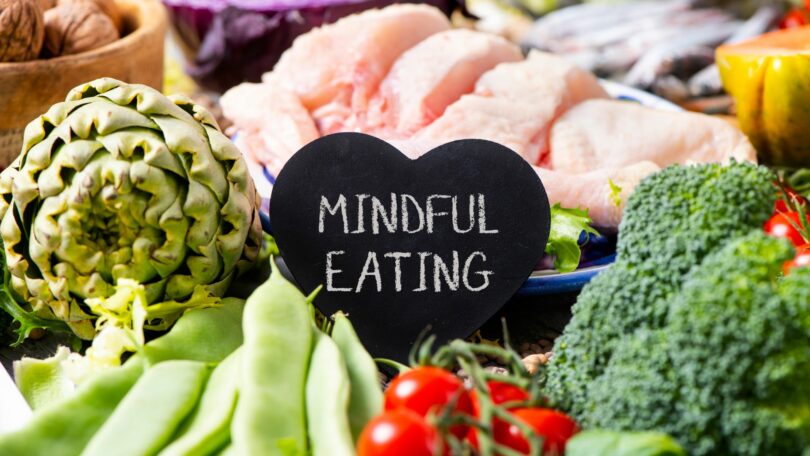 Imagem de vários vegetais, verduras e carne de frango e ao centro uma placa com os dizeres: Mindful Eating.
