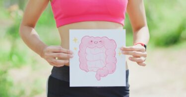 Imagem de uma mulher segurando uma placa com o desenho de um intestino. A foto traz o conceito da síndrome do intestino irritável.