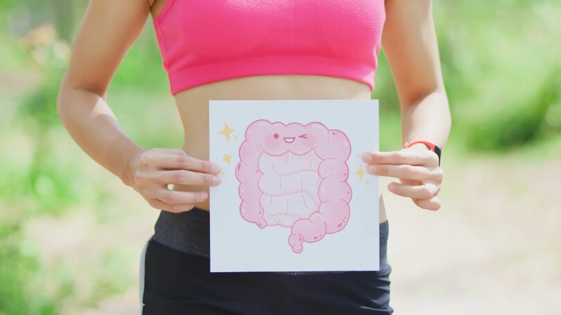 Imagem de uma mulher segurando uma placa com o desenho de um intestino. A foto traz o conceito da síndrome do intestino irritável.