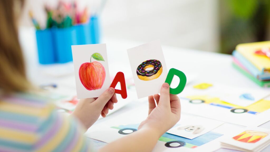 Imagem de uma criança associando as letras do do alfabeto com figuras de comida como a maçã e o donut's.
