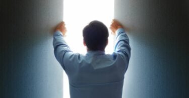Imagem de um homem abrindo uma fresta de luz, trazendo o conceito de uma abertura da fronteira intelectual.