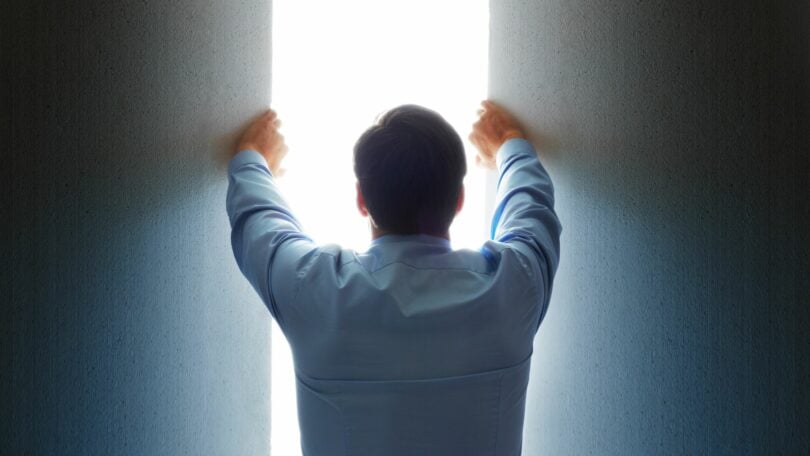 Imagem de um homem abrindo uma fresta de luz, trazendo o conceito de uma abertura da fronteira intelectual.