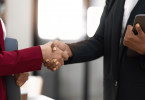 Duas mulheres de negócios estão se cumprimentando com as mãos no ambiente de trabalho.