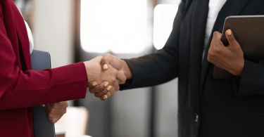 Duas mulheres de negócios estão se cumprimentando com as mãos no ambiente de trabalho.