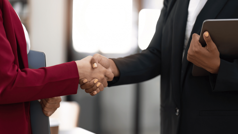 Duas mulheres de negócios estão se cumprimentando com as mãos no ambiente de trabalho.
