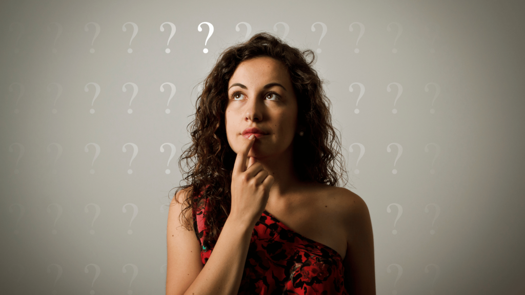 Uma mulher que olha para cima e tem a expressão de dúvida ou questionamento no rosto está no centro da imagem.