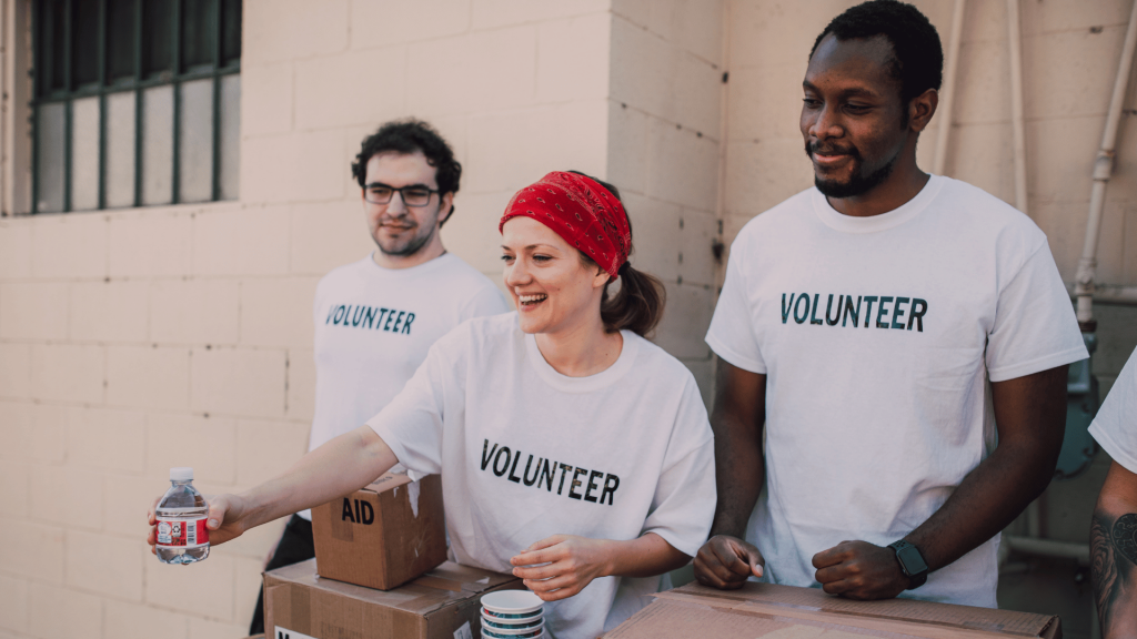 Três voluntários estão participando de uma ação de doações em um voluntariado.