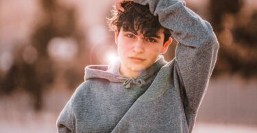 Imagem de um garoto adolescente usando um moletom cinza e brincos de argola. A foto faz alusão à série "Adolescência", da Netflix.