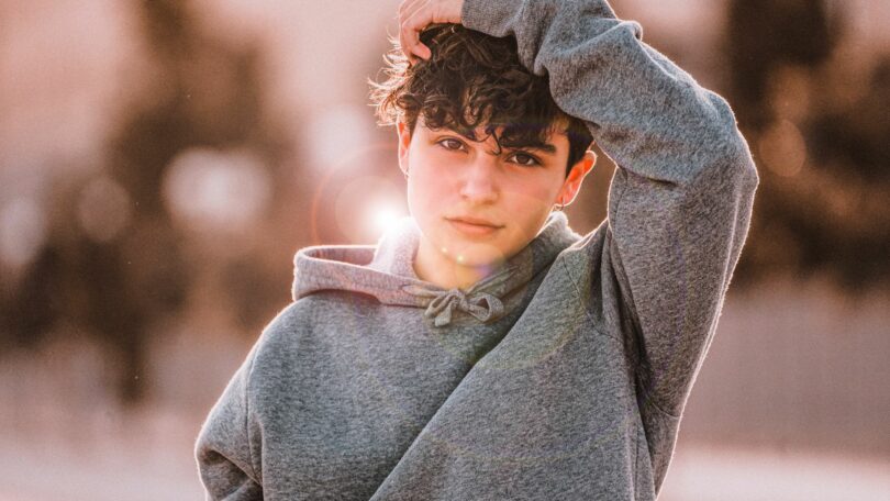 Imagem de um garoto adolescente usando um moletom cinza e brincos de argola. A foto faz alusão à série "Adolescência", da Netflix.