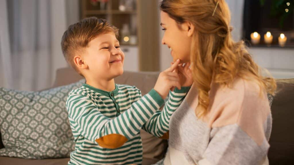 Imagem de mãe e filho sentandos em um sofá na sala conversando. O filho pergunta à mãe, se ela acredita em Deus.