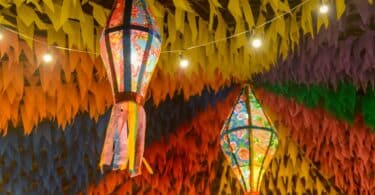 Imagem de bandeirinhas e balões coloridos pendurandos decorando a época das festas juninas.