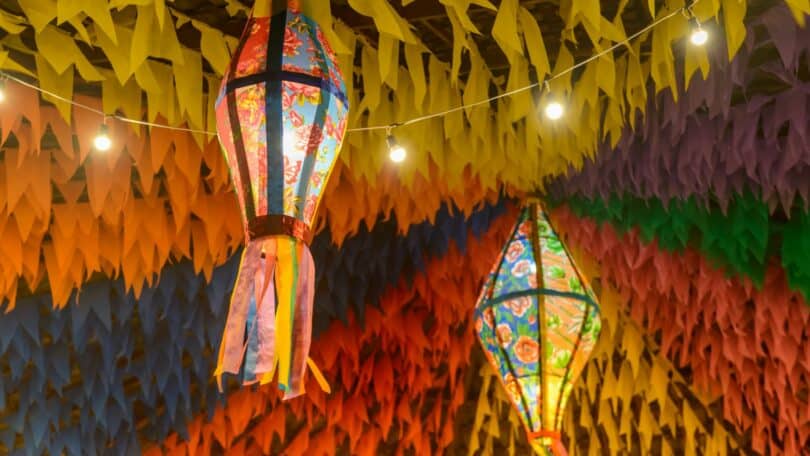 Imagem de bandeirinhas e balões coloridos pendurandos decorando a época das festas juninas.