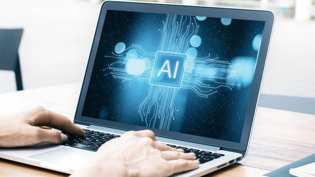 Imagem das mãos de uma pessoa, acessando o notebook para escrever um texto usando a IA.