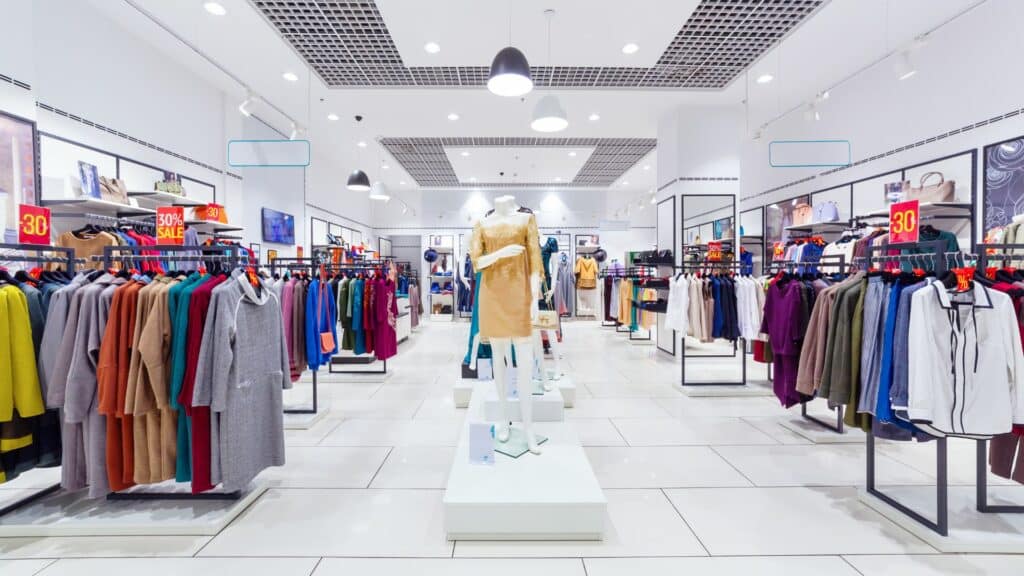 Imagem do interior de uma loja de roupas com variadas peças e estilos.