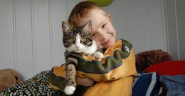 Imagem de um garotinho abraçando e segurando um gato. A foto traz o conceito de amor incondicional, empatia e desapego, mostrando que amar é cuidar, proteger e acolher, mas também é respeitar o tempo e a liberdade do outro.