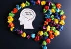 Imagem do contorno de uma cabeça humano onde está escrito Saúde Mental em inglês (Mental Health). Em volta do contorno, vários papéis coloridos amassados.