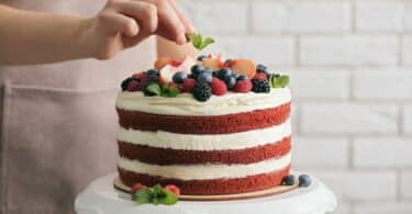 Imagem de um bolo de festa red velt coberto com frutas variadas, recheado com creme de Chantilly.
