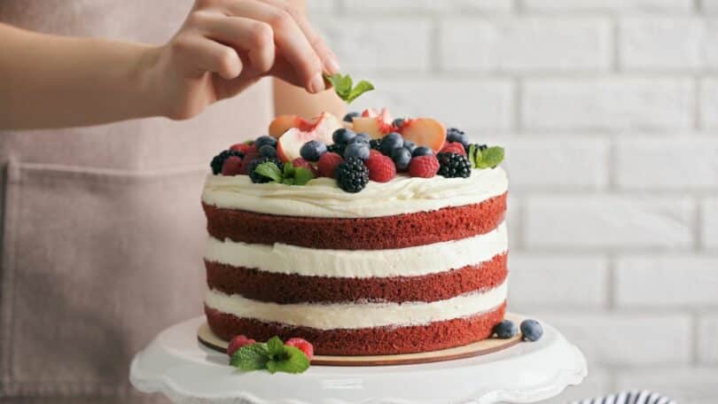 Imagem de um bolo de festa red velt coberto com frutas variadas, recheado com creme de Chantilly.