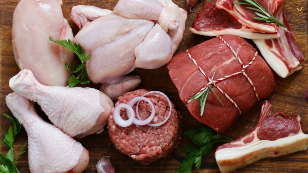 Imagem de carne de frango, carne vermelha sendo preparadas para armazenamento.