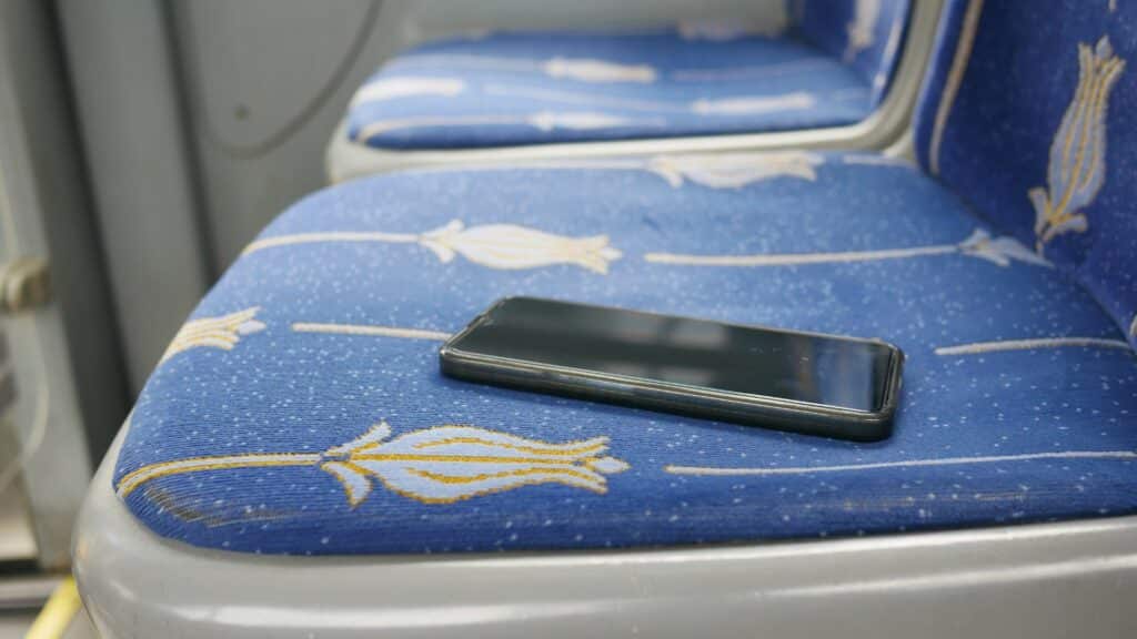 Imagem de um celular perdido sobre um banco dentro do ônibus.