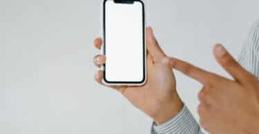 Imagem de um mão masculina segurando um celular com capa branca. O celular havia sido perdido e foi encontrado.