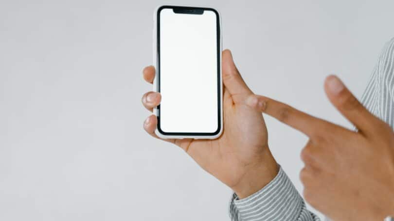 Imagem de um mão masculina segurando um celular com capa branca. O celular havia sido perdido e foi encontrado.