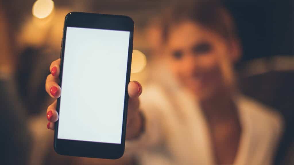 Imagem de uma mulher segurando um celular que estava perdido.