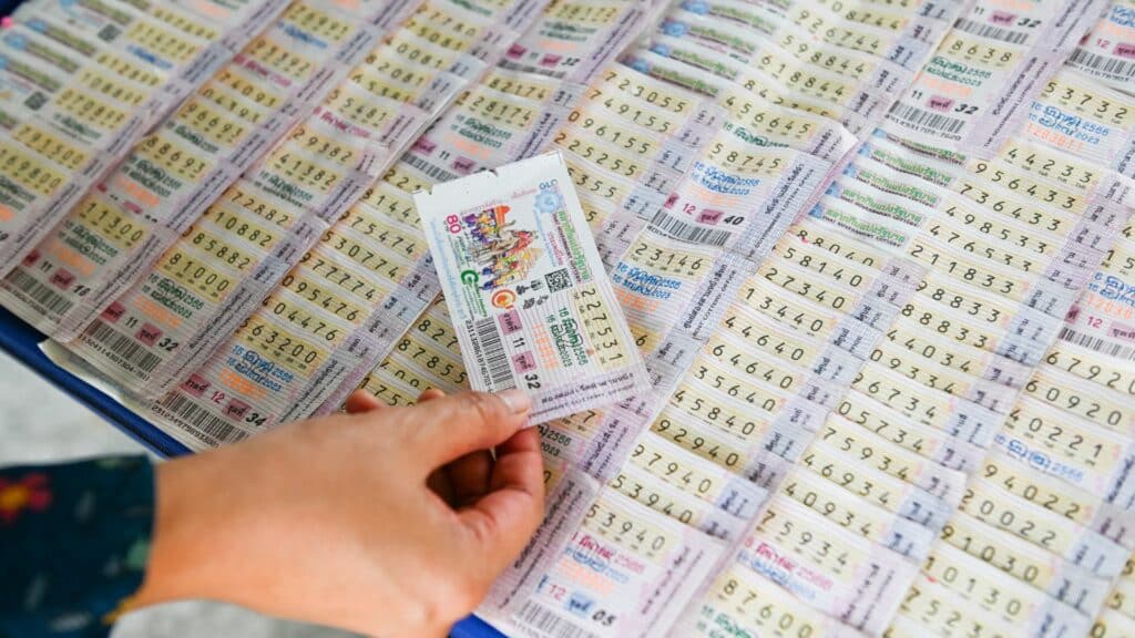 Imagem de uma mulher segurando um bilhete premiado da loteria e ao fundo, vários outros bilhetes numerados.